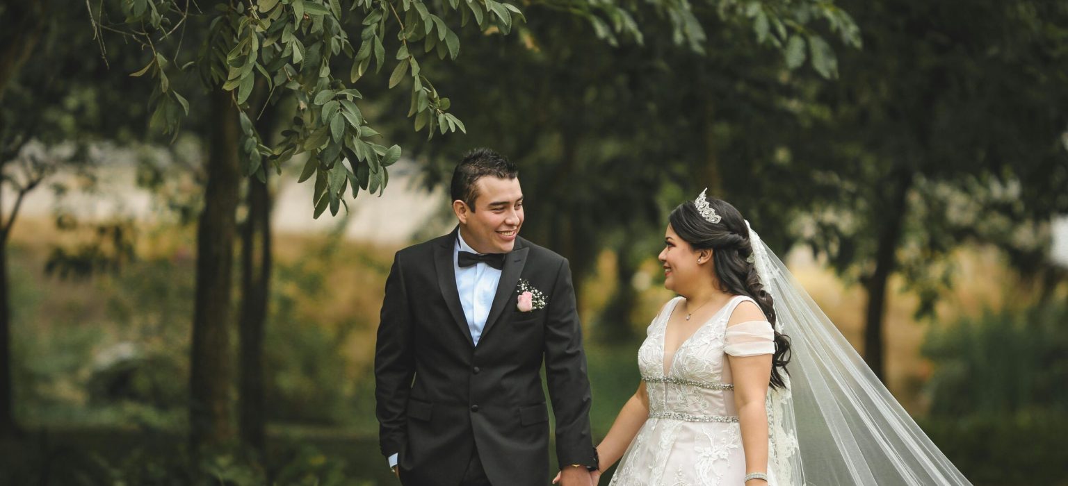 couple walking in a garden while holding hands and looking at each other